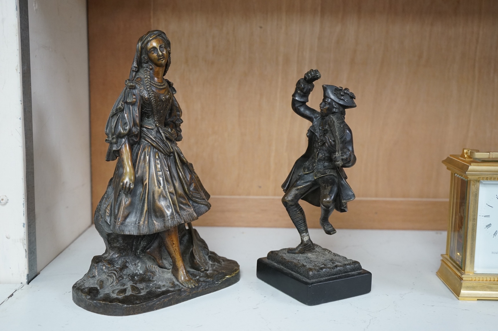 A small bronze figure of a male violinist and another bronze female figure with a lute against a rock, tallest 23cm high
